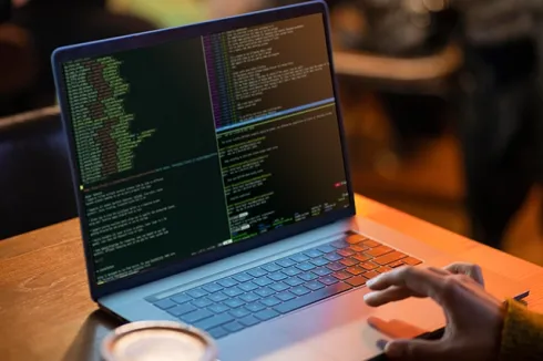 "Laptop displaying code with a hand typing, highlighting IT solutions, cloud hosting, business email, and cloud email by Elevation Technology.