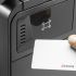 A close-up of a hand using a Kyocera ID card to activate the card reader on a printer.